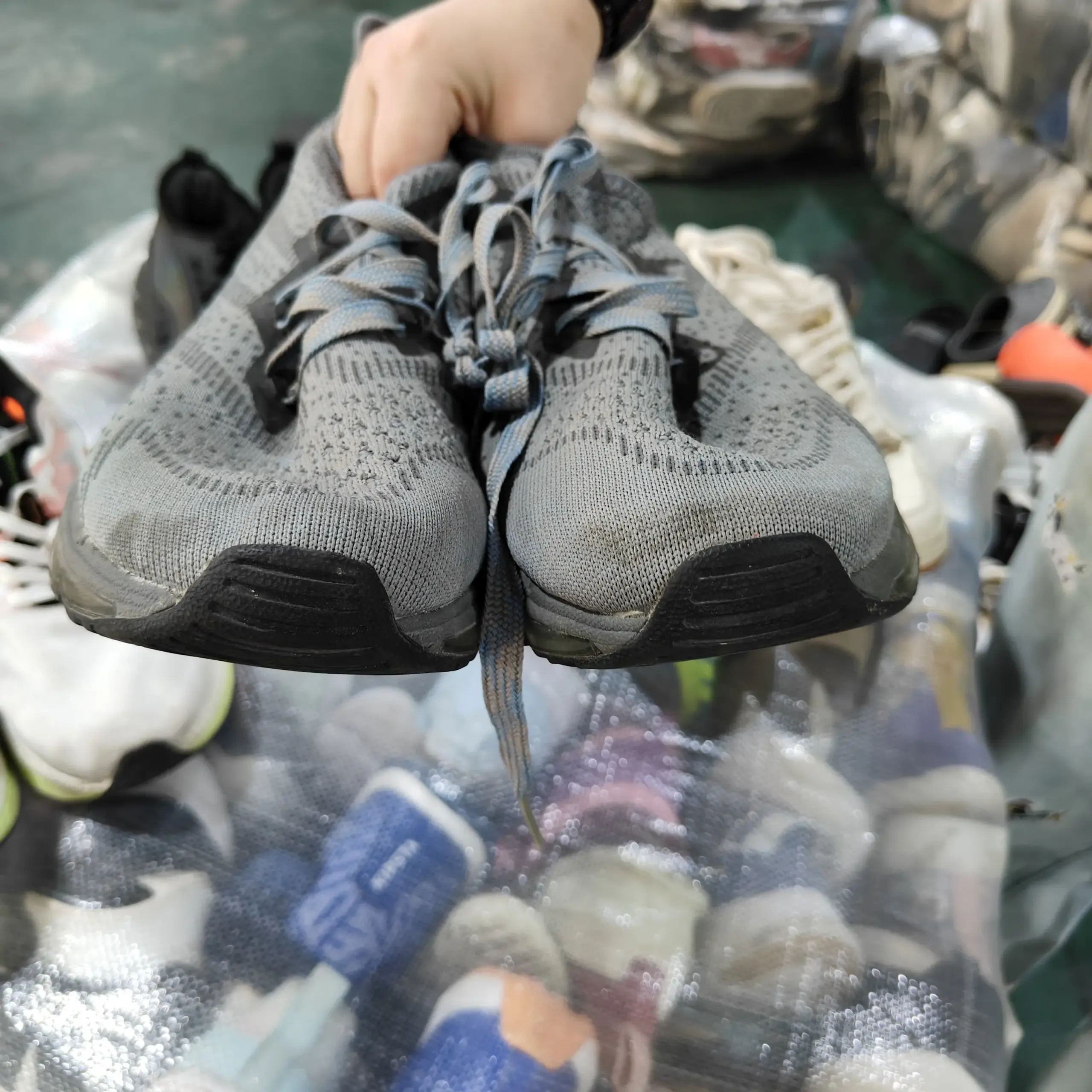 Grey athletic sneakers with black soles and laces, suitable for wholesale used shoe exports from China.