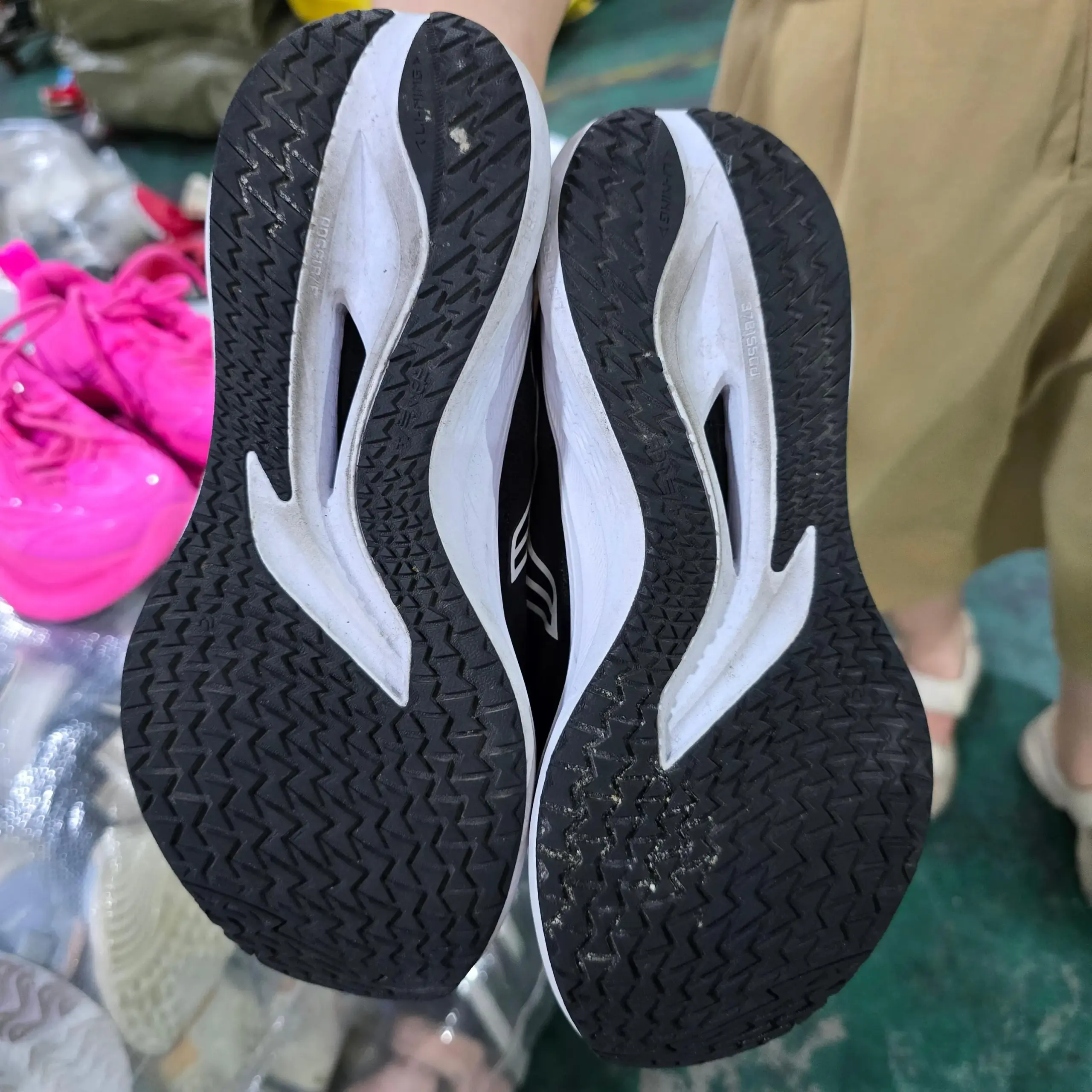 Black and white athletic shoes with zigzag patterned soles, suitable for wholesale export from China.
