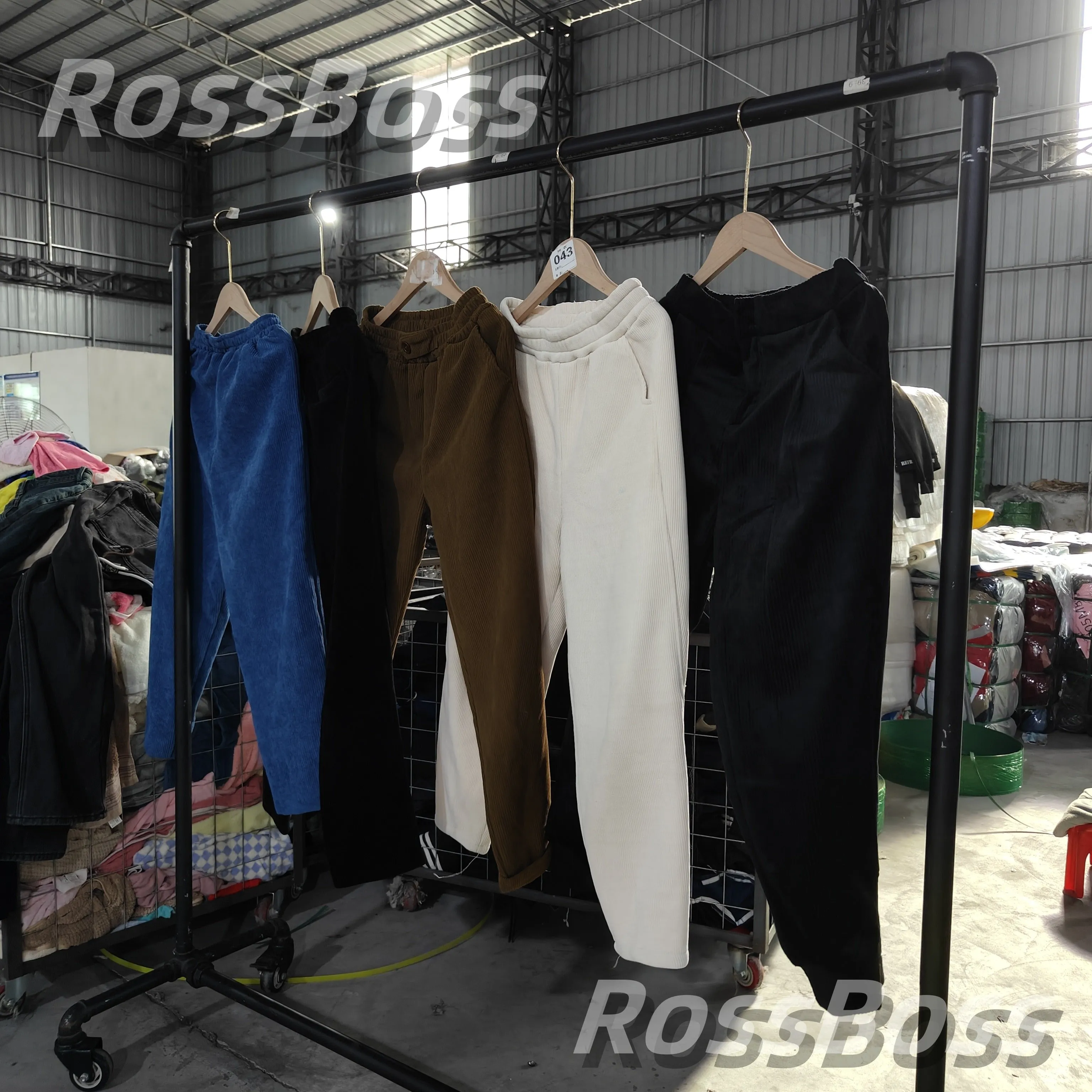 Blue, black, brown, white, and black corduroy pants on hangers.