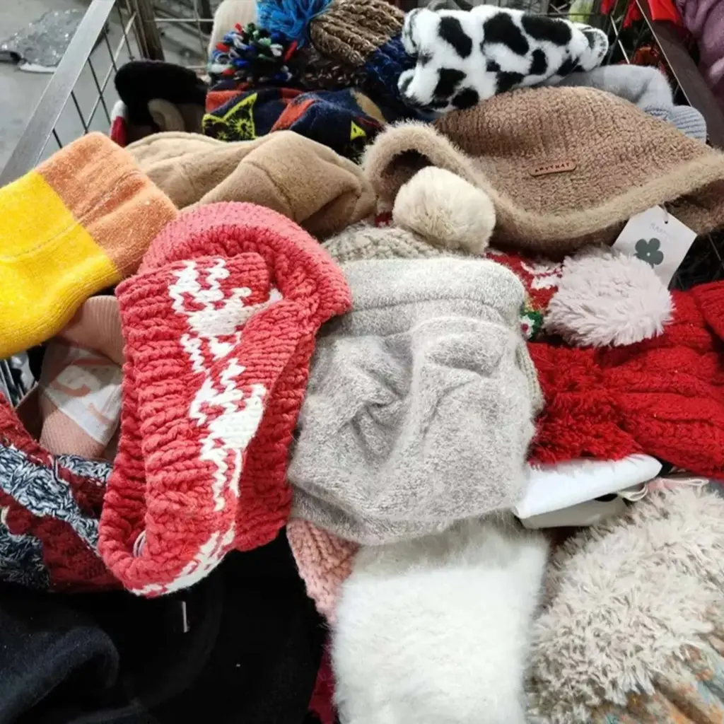 Accessories: A variety of colorful winter hats, including red with white patterns, gray with pom-poms, brown, and black and white cow print, available in different styles and colors for wholesale purchase from RossBoss, a factory-direct supplier of used clothing accessories.