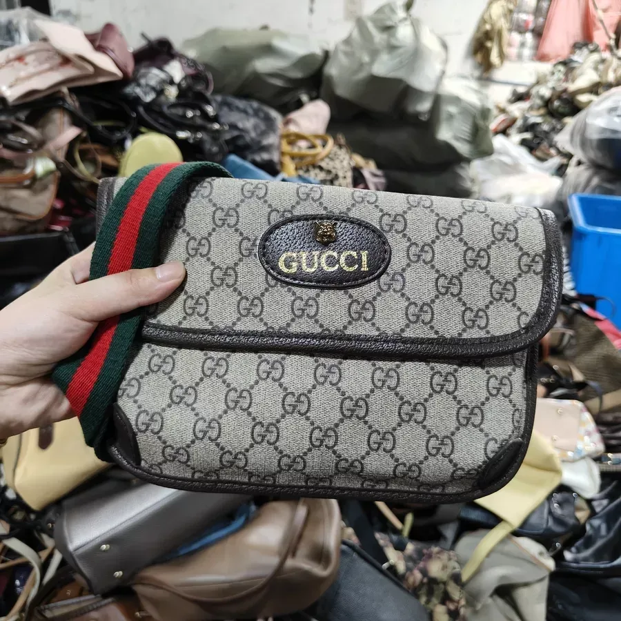 Gucci crossbody bag with classic monogram pattern and red and green striped strap.