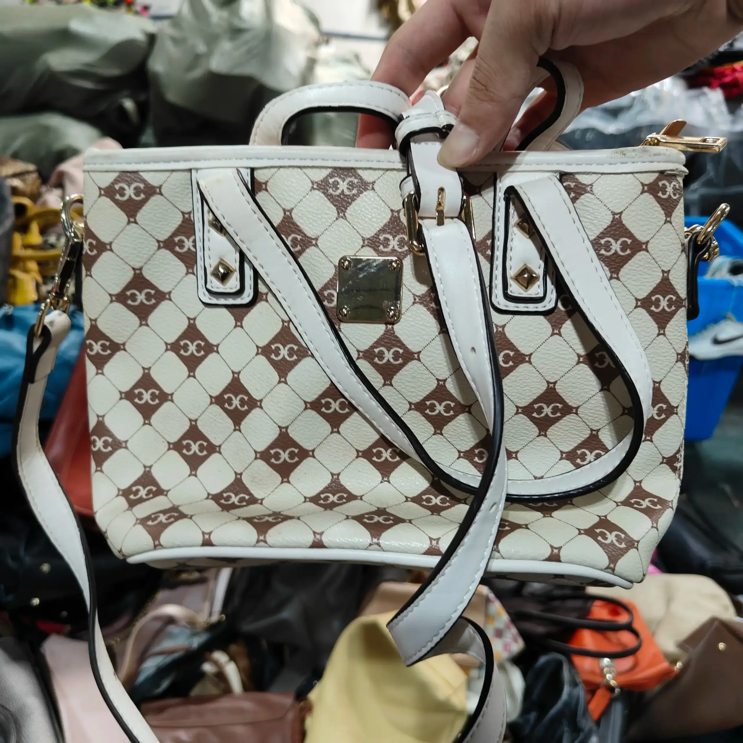 White and brown patterned ladies' bag with gold hardware and adjustable strap.