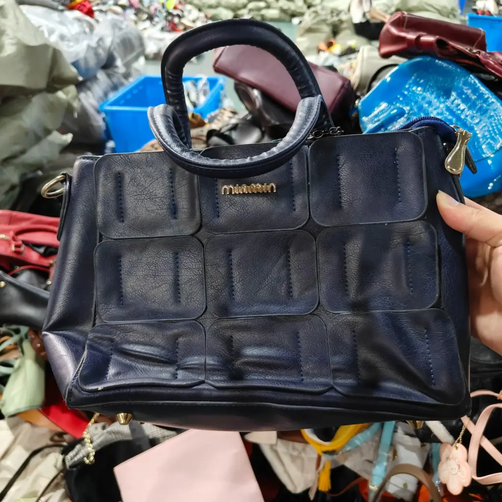 Blue leather handbag with gold hardware and embossed pattern.