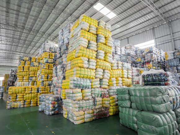 Compressed bales of used clothing stacked in a warehouse awaiting export packing